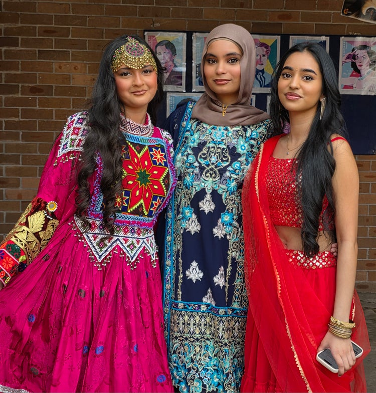 Three girls dressed in traditional dress, including sari outfits as well as jewellery and accessories.
