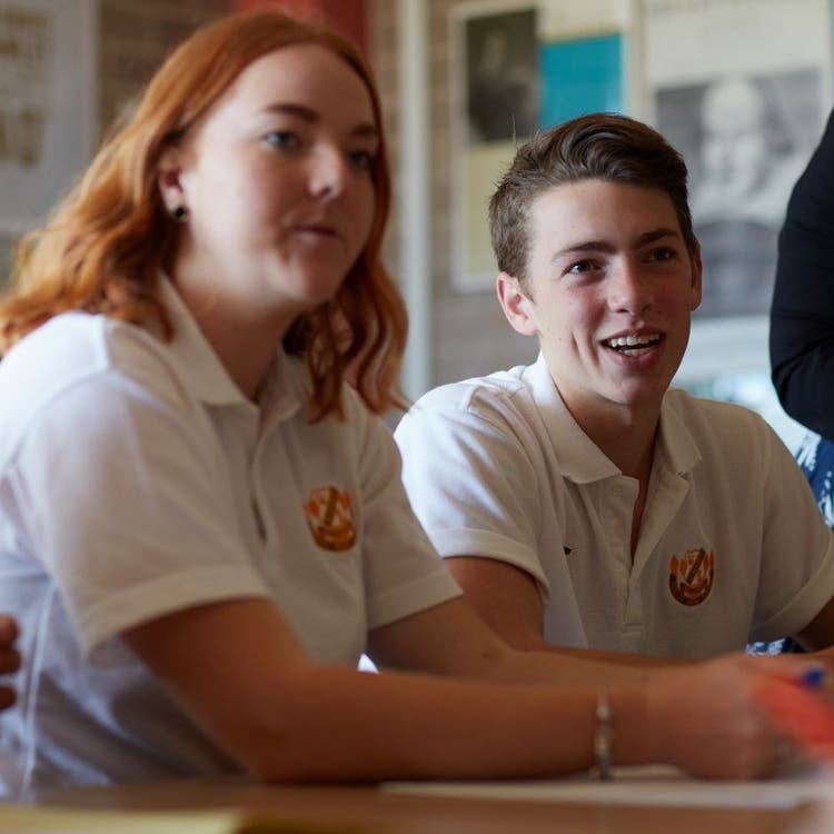 Two students sitting at a desk, looking forward.